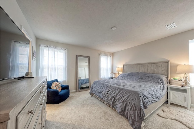 bedroom with baseboards, visible vents, and light colored carpet