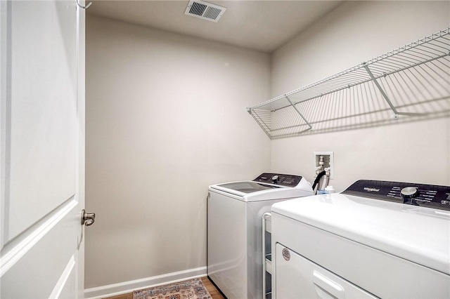 washroom with wood finished floors, washer and dryer, laundry area, baseboards, and visible vents