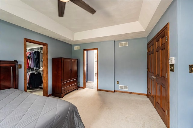 bedroom with light colored carpet, baseboards, a walk in closet, and visible vents