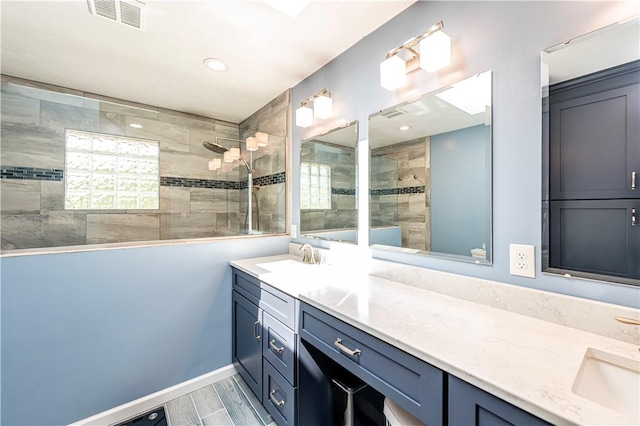 bathroom featuring baseboards, visible vents, vanity, and a walk in shower