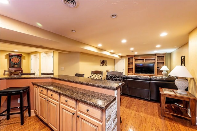 kitchen with recessed lighting, light wood-type flooring, visible vents, and a breakfast bar area