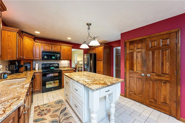 kitchen with light stone counters, backsplash, a sink, a center island, and black appliances