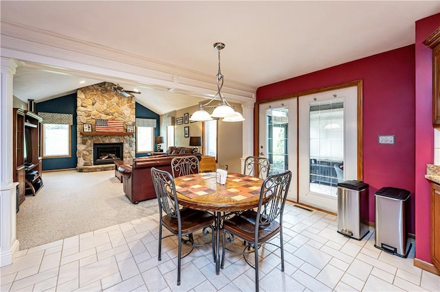 dining area featuring vaulted ceiling, a stone fireplace, and baseboards