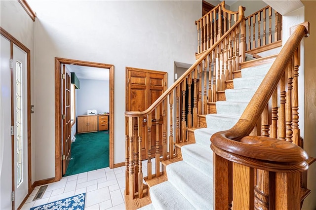 stairs with a high ceiling, carpet flooring, baseboards, and visible vents