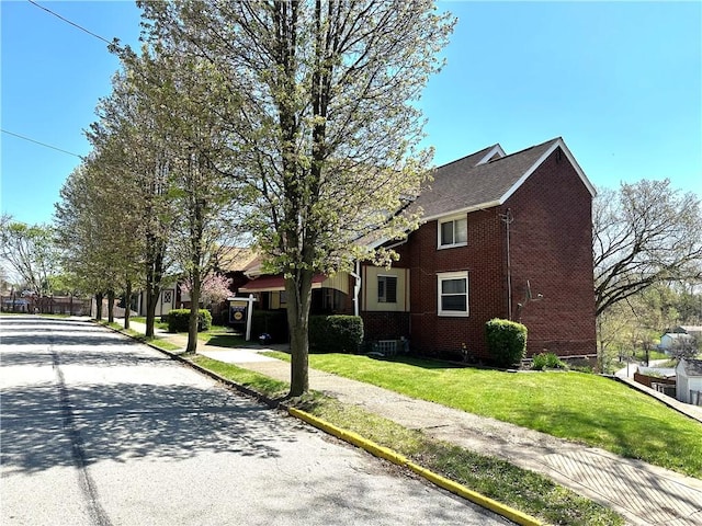view of side of home with brick siding and a yard