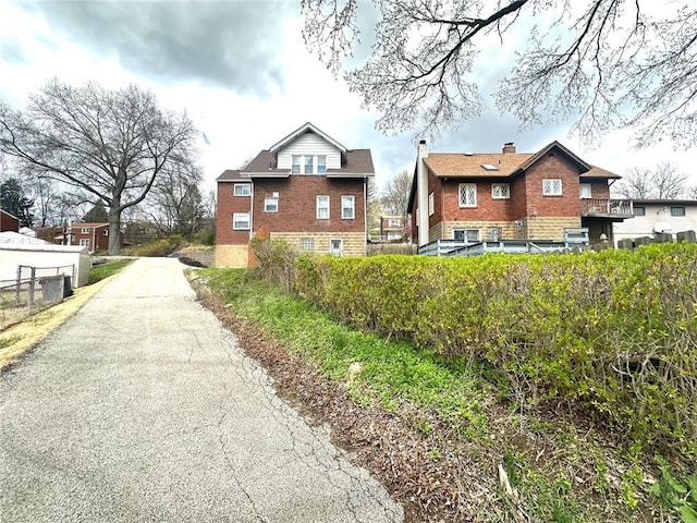 exterior space with a chimney, fence, aphalt driveway, and brick siding