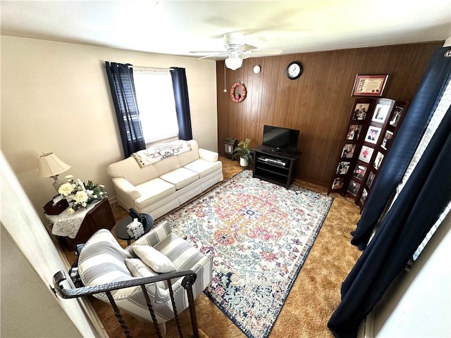 carpeted living room with wood walls and a ceiling fan