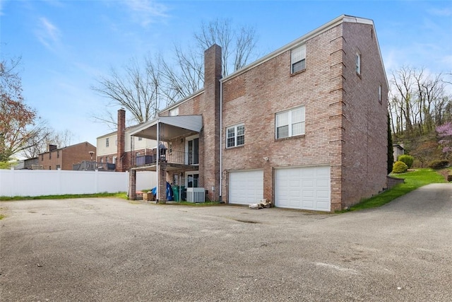2007 Garrick Dr, Churchill Boro, PA 15235 - back of property with central AC, a chimney, an attached garage, fence, and brick siding