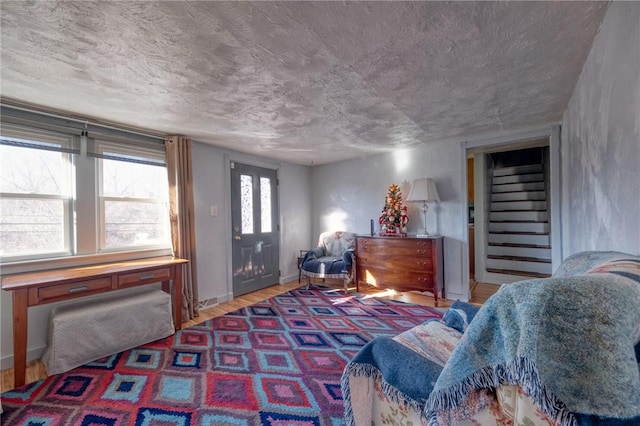 bedroom with wood finished floors, baseboards, and a textured ceiling