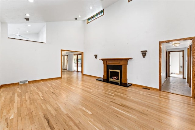 86 Lambeth Dr, Upper St Clair, PA 15241 - unfurnished living room with a high ceiling, a warm lit fireplace, light wood finished floors, and visible vents