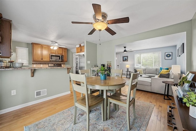 dining room featuring baseboards, light wood-style flooring, visible vents, and ceiling fan
