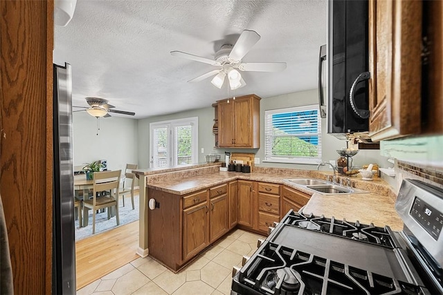 kitchen featuring a peninsula, a ceiling fan, stainless steel appliances, and a sink