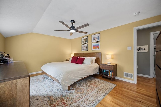 bedroom featuring light wood-type flooring, visible vents, a ceiling fan, and baseboards