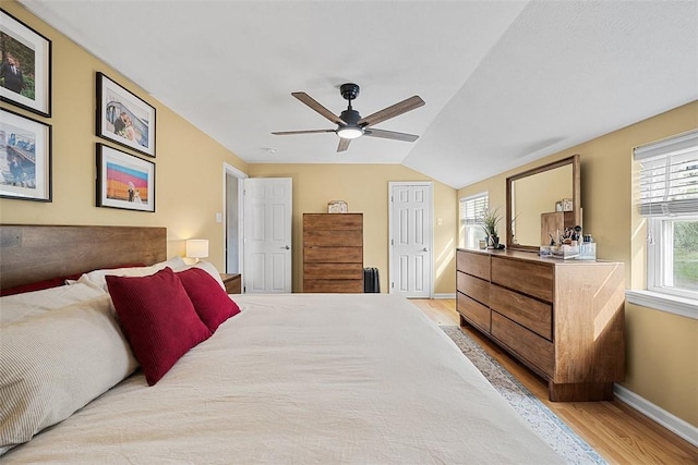 bedroom featuring ceiling fan, baseboards, lofted ceiling, and light wood-style flooring