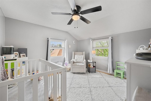 bedroom with a crib, vaulted ceiling, baseboards, and ceiling fan