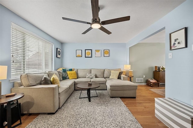 living area with wood finished floors, visible vents, and a ceiling fan