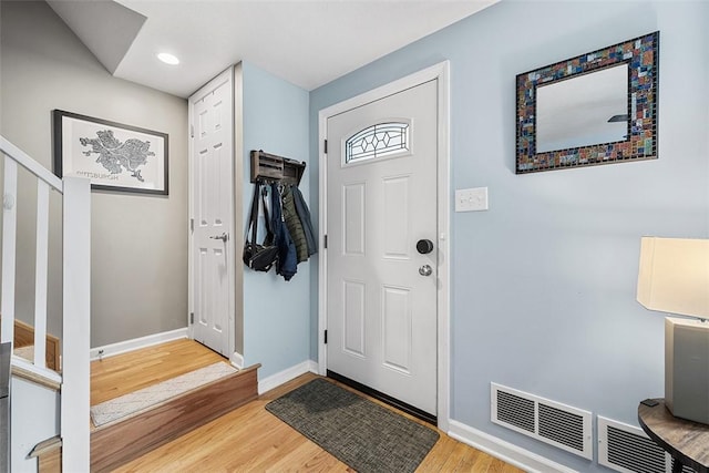 foyer with recessed lighting, wood finished floors, visible vents, baseboards, and stairs