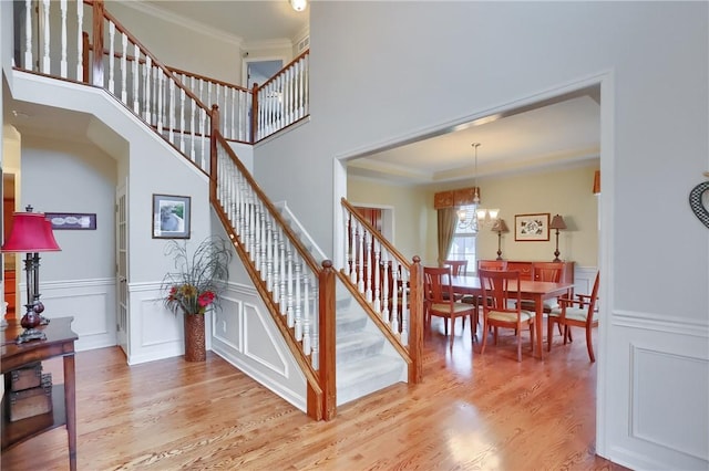 404 Plum Ct, Cranberry Twp, PA 16066 - stairs featuring crown molding, wood finished floors, a chandelier, a decorative wall, and wainscoting