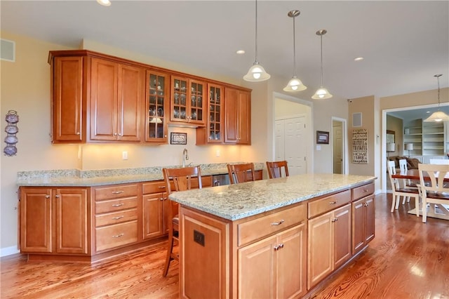 404 Plum Ct, Cranberry Twp, PA 16066 - kitchen featuring wood finished floors, decorative light fixtures, brown cabinets, light stone counters, and recessed lighting