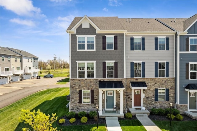 townhome / multi-family property with stone siding and a front yard