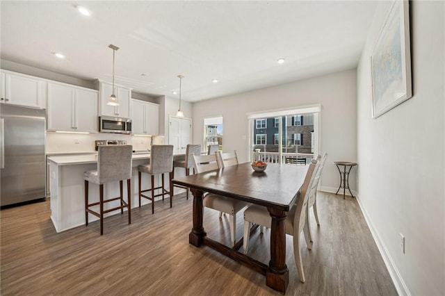 dining space with baseboards, wood finished floors, and recessed lighting