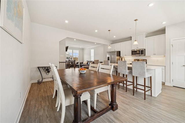 dining area featuring baseboards, light wood-style floors, and recessed lighting