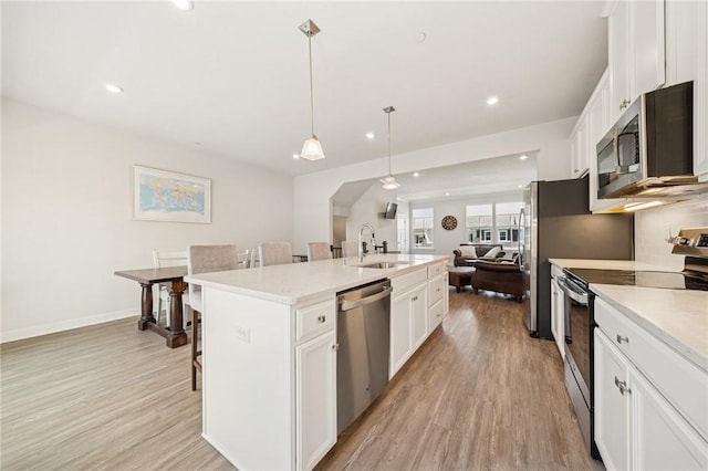 kitchen with open floor plan, light wood-style flooring, a sink, and appliances with stainless steel finishes