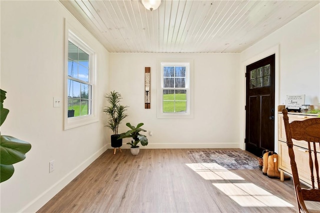 interior space with wood ceiling, a wealth of natural light, wood finished floors, and baseboards