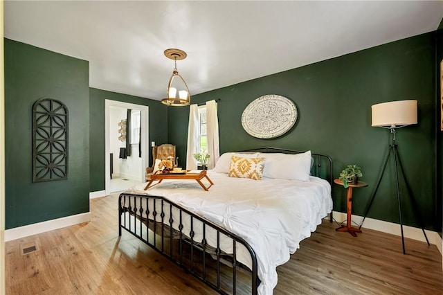 bedroom with baseboards, wood finished floors, and visible vents