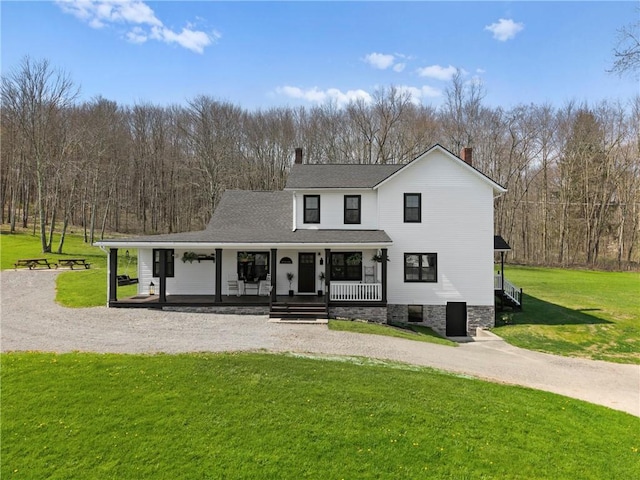 view of front facade featuring a front yard, a porch, a chimney, and curved driveway