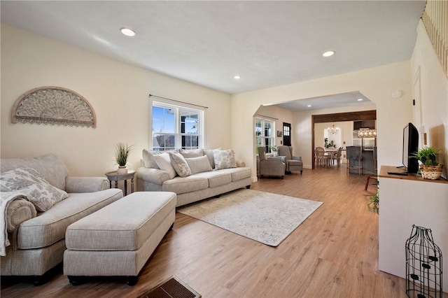 living room featuring light wood finished floors, arched walkways, and recessed lighting