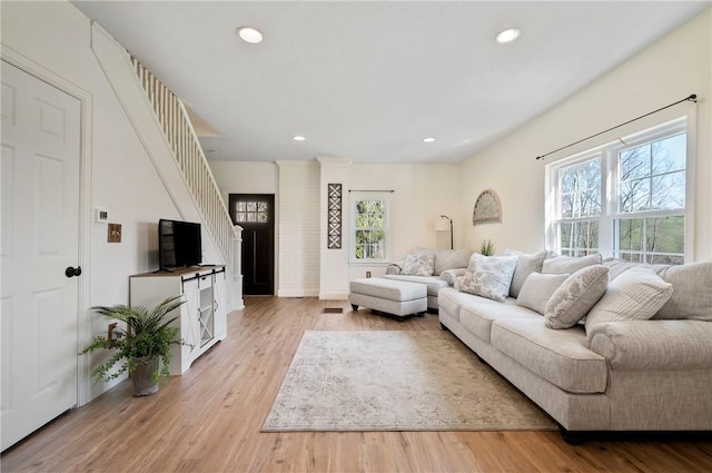 living area with light wood-style floors, stairway, and a wealth of natural light