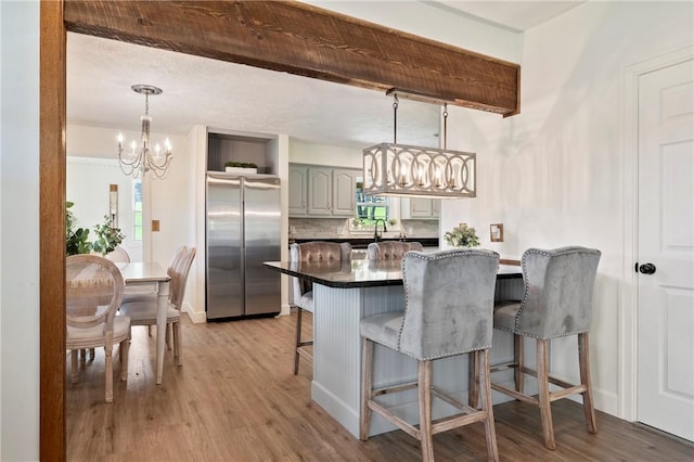 kitchen featuring freestanding refrigerator, light wood-type flooring, a kitchen breakfast bar, and an inviting chandelier
