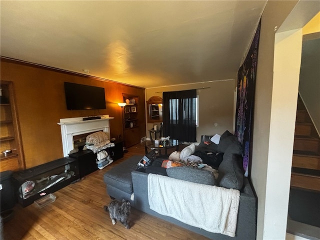 living room featuring wood finished floors, a fireplace with raised hearth, and stairway