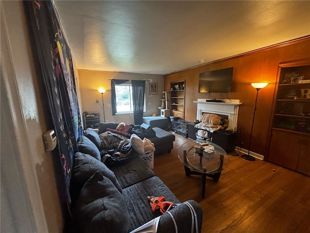 living area featuring built in shelves, wood finished floors, and a fireplace