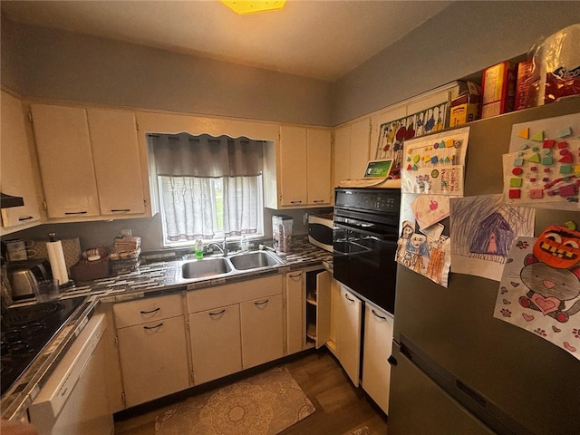 kitchen featuring oven, freestanding refrigerator, a sink, and dark wood-type flooring