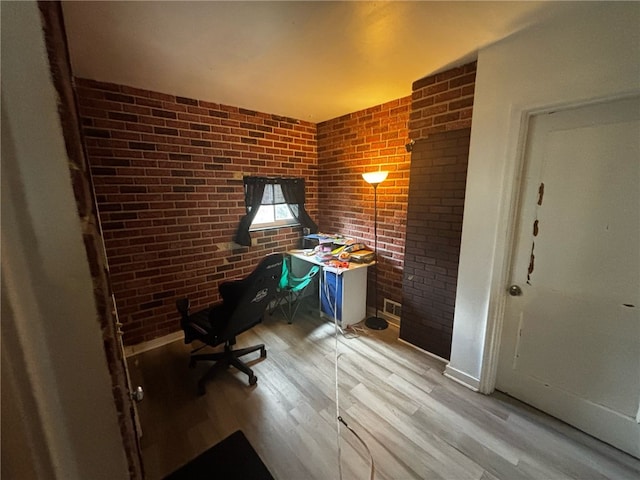 office with brick wall, baseboards, and light wood-type flooring
