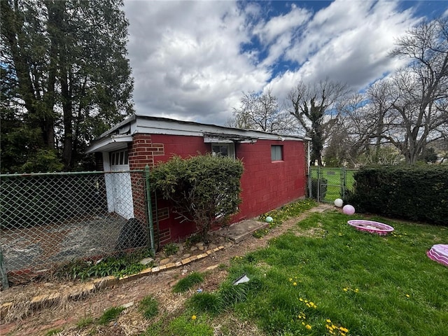 view of side of property featuring concrete block siding, a lawn, and fence