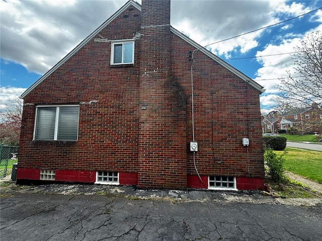 view of property exterior with a chimney and brick siding