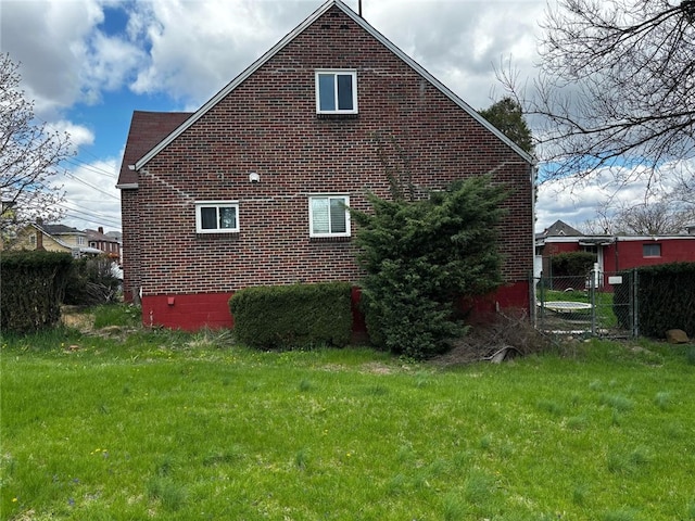 view of home's exterior featuring fence, brick siding, and a yard