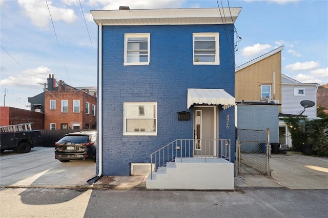 view of front of house featuring a gate, fence, and brick siding