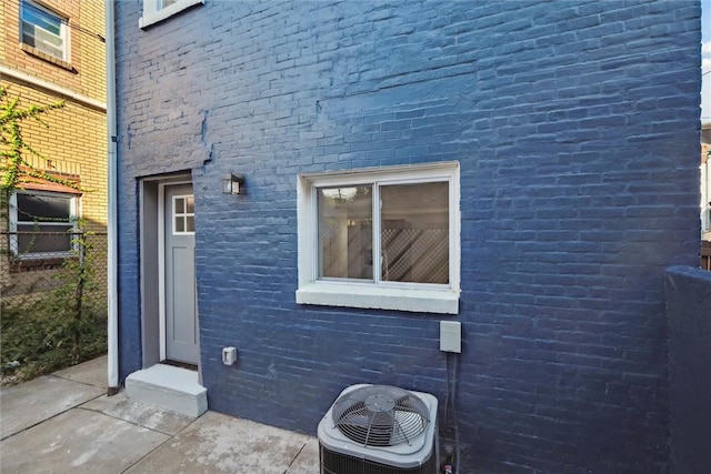 view of side of home featuring brick siding and cooling unit