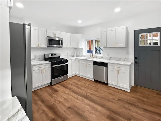 kitchen with dark wood-style flooring, stainless steel appliances, white cabinetry, and a sink