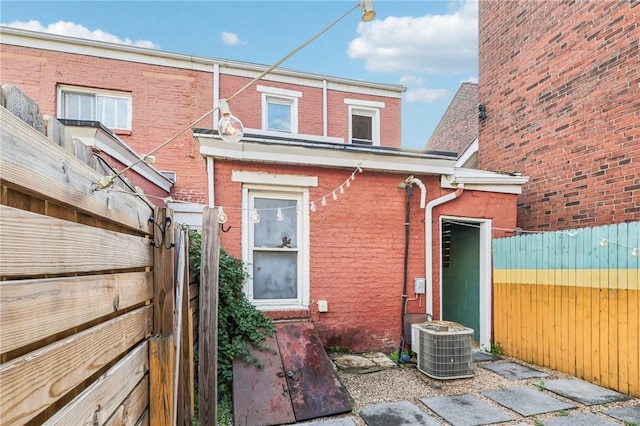 back of property featuring a fenced backyard, brick siding, and central air condition unit