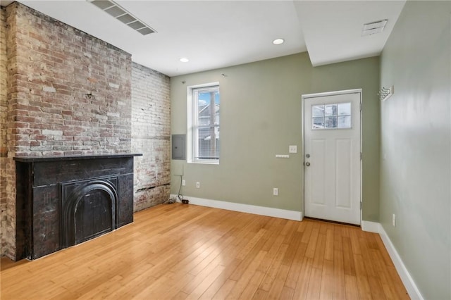 unfurnished living room featuring baseboards, wood finished floors, visible vents, and a fireplace