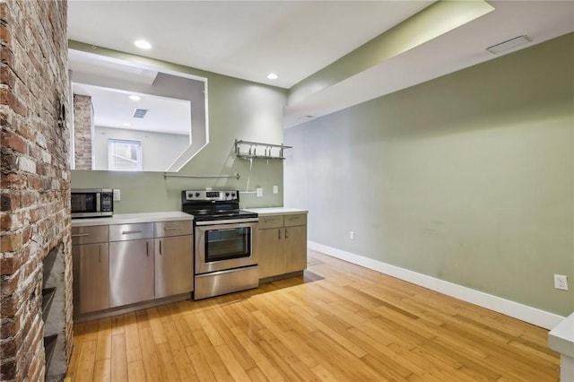 kitchen featuring stainless steel appliances, light wood-style flooring, baseboards, visible vents, and light countertops