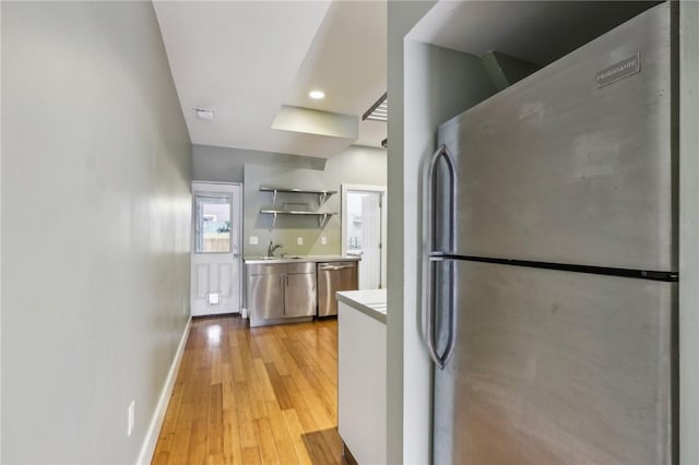 kitchen with light countertops, open shelves, light wood-type flooring, baseboards, and appliances with stainless steel finishes