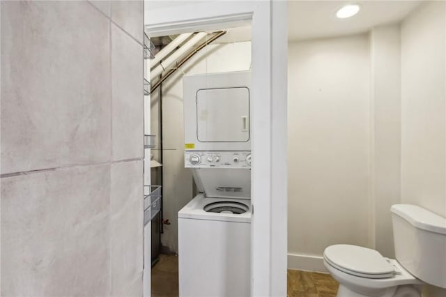 bathroom featuring toilet and stacked washer / drying machine