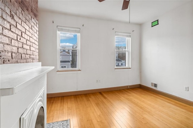empty room with baseboards, light wood-style flooring, visible vents, and ceiling fan