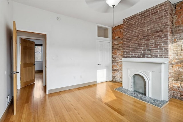 unfurnished living room with ceiling fan, baseboards, hardwood / wood-style floors, and a fireplace